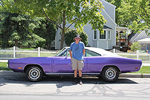 Andrew Gramer poses in front of one of his fathers most prized possessions, a purple Dodge Charger.