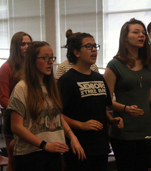Lily Chidester, in the front row at the left, warms up with the Madrigals Choir.
