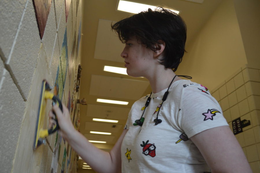 Miranda Roland prepares her spot on the art hall wall to paint.