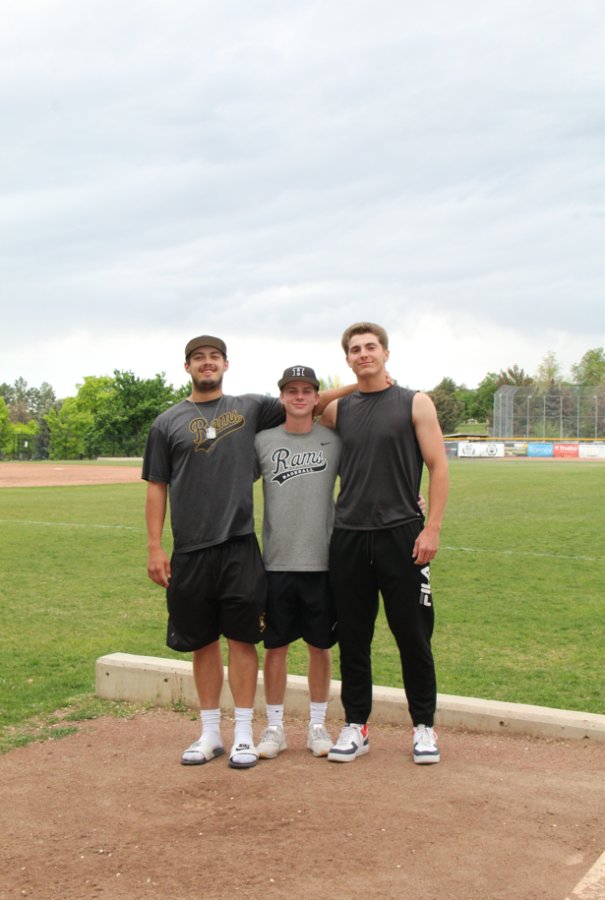 Greg Harrold, Charlie Koelliker, and Alta Huntsman stand together in front of the baseball field.