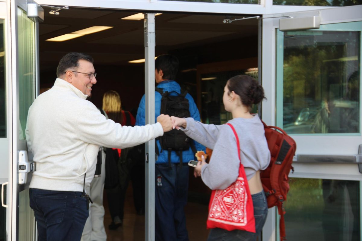 Principal Jeremy Chatterton greeting a student at the door before school starts.