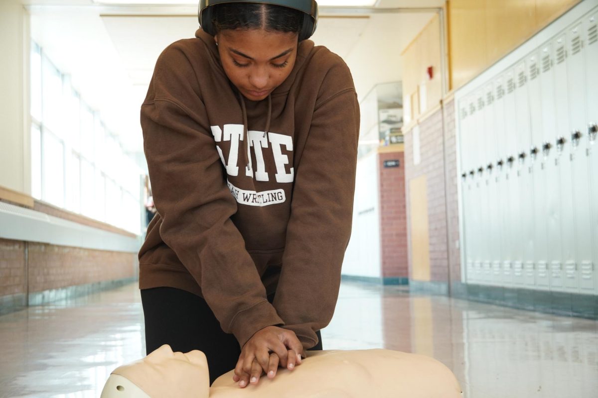 Miah Cook demonstrates her CPR technique on a dummy simulator.