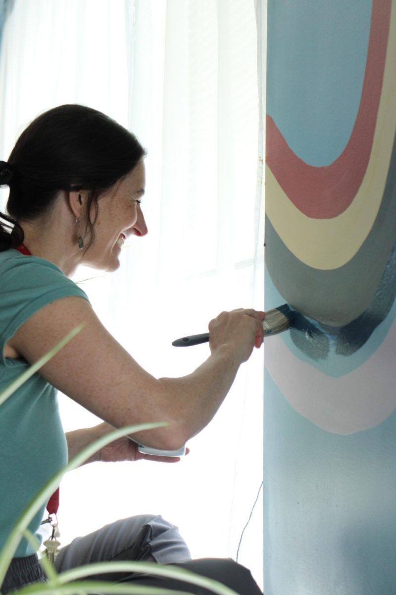 Aubrey Gamble paints a rainbow on her wall.