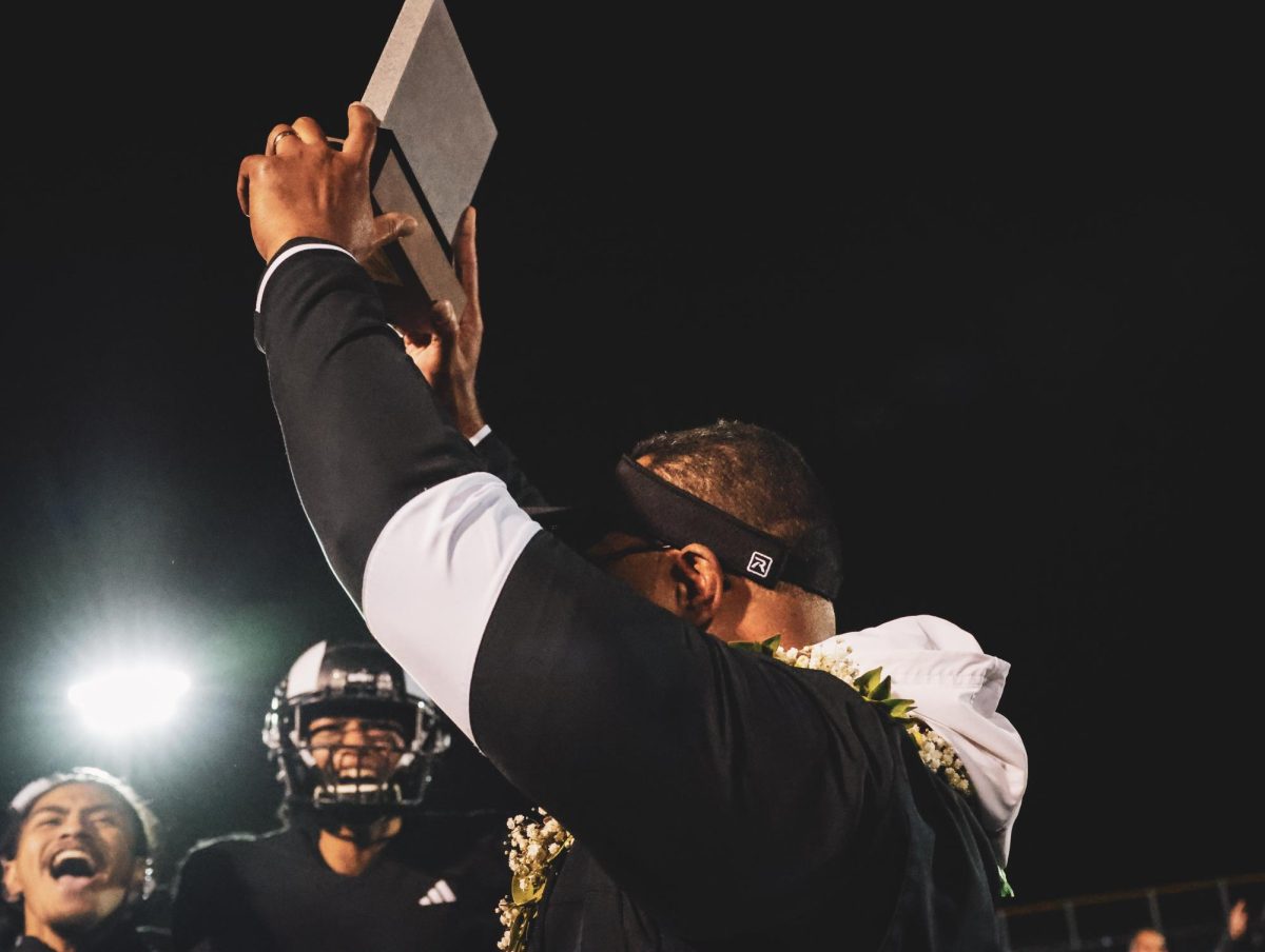 Head Coach Kautai Olevao hoists the Region Championship trophy.